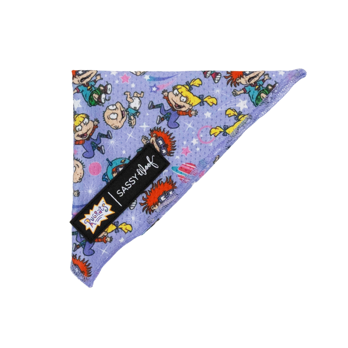 The Sassy Woof Dog Bandana - Nickelodeon Rugrats™ is a purple, triangular accessory with cartoon Angelica, Chuckie, and Tommy, colorful stars and dots, plus two black and white brand tags—perfect for any fan of Rugrats dog accessories.