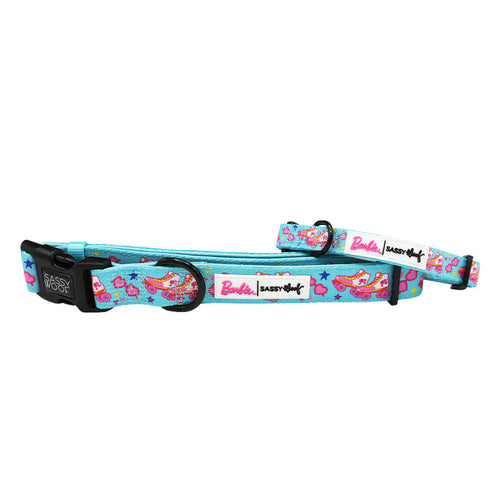 The Sassy Woof Dog Collar – BARBIE™ On a Roll features light blue color and colorful Barbie-themed designs with Barbie in a car, pink stars, and Barbie & Sassy Woof logos. It’s adjustable with a black buckle and sturdy metal ring.