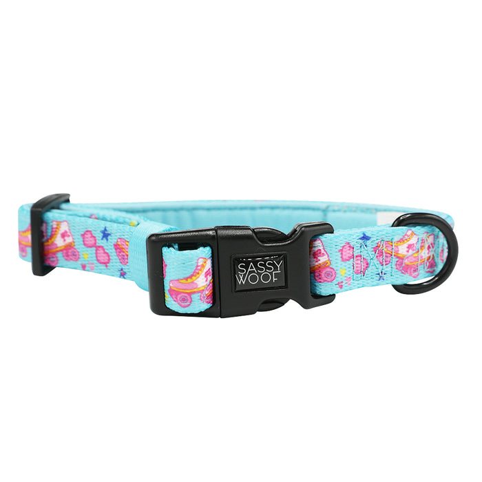The Dog Collar - BARBIE™ On a Roll by Sassy Woof is blue with pink, yellow, and purple hearts and skates. It features a black plastic SASSY WOOF buckle, sturdy black metal leash ring, and is part of the Barbie x Sassy Woof collection.