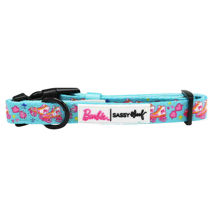 The Sassy Woof Dog Collar - BARBIE™ On a Roll is blue with pink and yellow designs, a black buckle, and a white tag featuring Barbie and Sassy Woof logos.