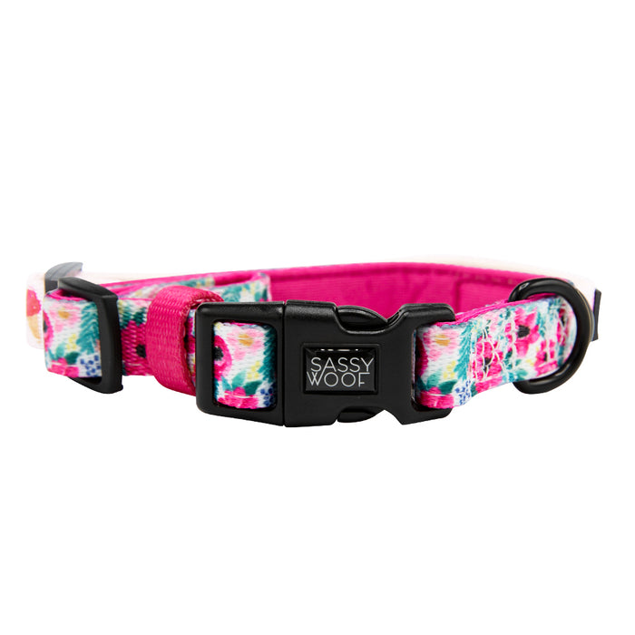 The Sassy Woof Dog Collar - Floral Frenzy features a floral pattern, pink inner lining, adjustable fit, black plastic buckle, and branded clasp—ideal to pair with your pet’s favorite reversible harness.