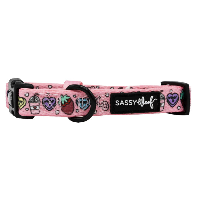 The Sassy Woof Dog Collar - I Chews You is a pink neoprene collar with doodle designs (strawberries, drinks, hearts), an adjustable fit, sturdy leash attachment, black buckle, and a black Sassy Woof label.