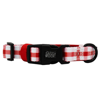The Sassy Woof Dog Collar - Picnic Fur Two features a red and white plaid design, an adjustable fit, sturdy D-ring, black plastic buckle, and the Sassy Woof logo.