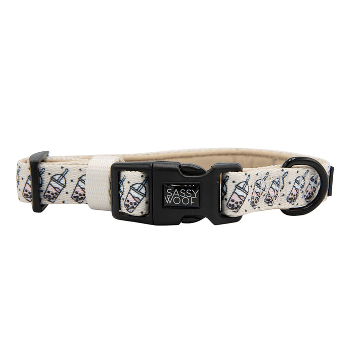 The Sassy Woof "Spill the Tea" dog collar is beige with a bubble tea pattern, features a black plastic buckle, sturdy D-ring for leash attachment, and adjustable fit.