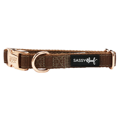 The Dog Collar - Teddy by Sassy Woof is a brown fabric adjustable collar with rose gold metal hardware, a sturdy D-ring, buckle, and a black label with "Sassy Woof" in white script.