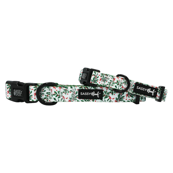 Two "Under the Mistletoe" dog collars by Sassy Woof feature black hardware and a festive green and red holly pattern on white neoprene—perfect matching holiday accessories for your pet.