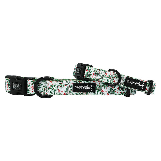 Two "Under the Mistletoe" dog collars by Sassy Woof feature black hardware and a festive green and red holly pattern on white neoprene—perfect matching holiday accessories for your pet.