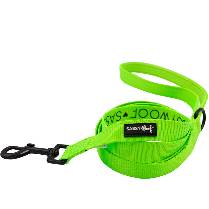 The Sassy Woof Dog Four Piece Bundle in neon green features a vibrant leash with a black metal clip, shown coiled on a white background—pair it with the adjustable collar for extra style and comfort.