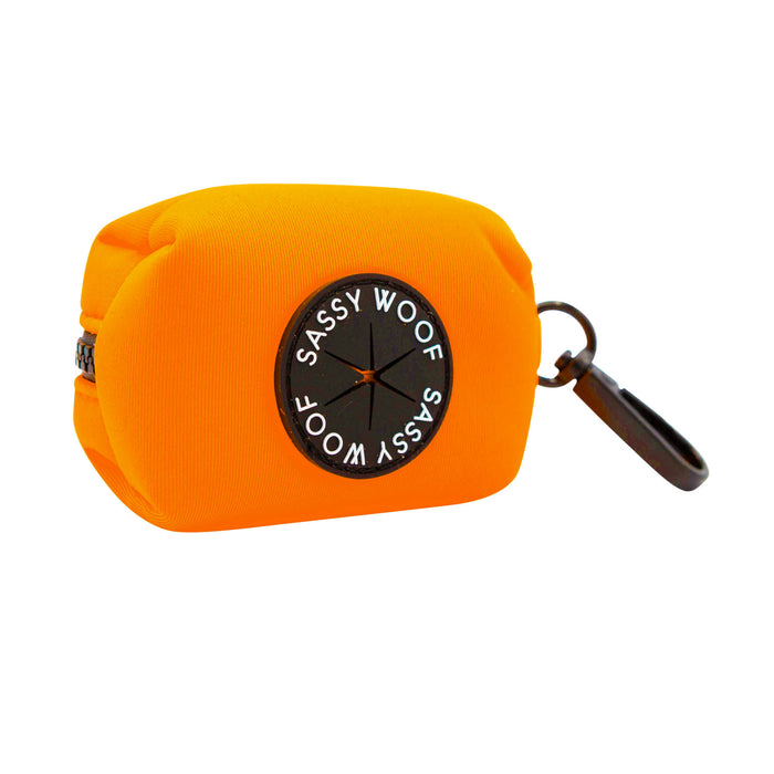 The Sassy Woof Dog Four Piece Bundle in Neon Orange features a bright rectangular waste bag holder with zipper, black clip, and circular Sassy Woof patch—perfect for walks when paired with your favorite adjustable collar.