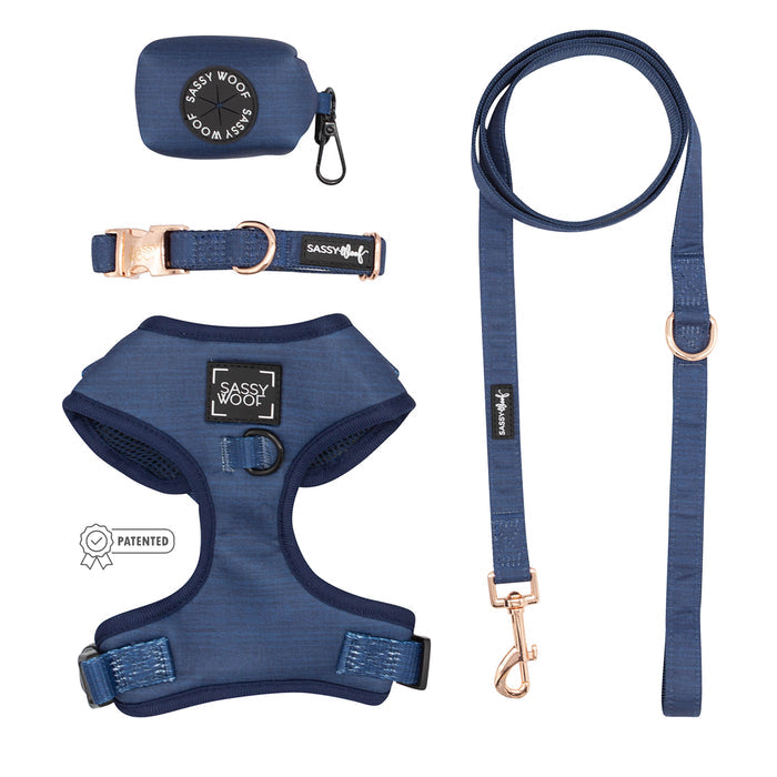 The Sassy Woof Dog Four Piece Bundle - Twilight features a navy blue adjustable harness, leash, collar, and waste bag holder with rose gold hardware, all arranged neatly on a white background.
