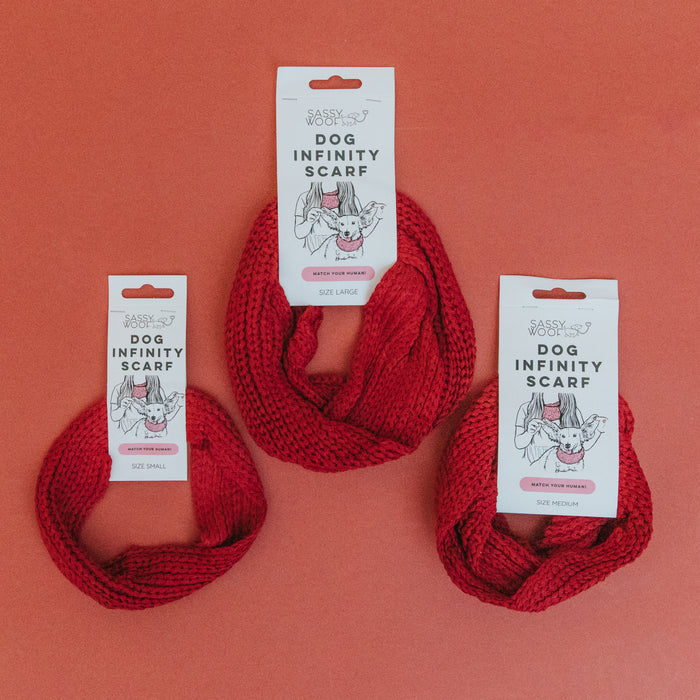 Three Sassy Woof Dog Infinity Scarves - Red are shown in small, medium, and large sizes on an orange background, each with branded packaging—the ideal cozy accessory for your pup’s cold weather walks.
