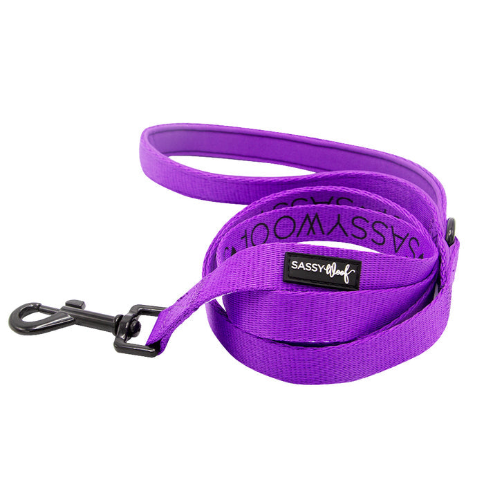 The Sassy Woof Dog Two Piece Bundle in Neon Purple features a coiled leash with a black metal clasp and branded label, ideal for matching with a neon dog harness, shown against a white background.