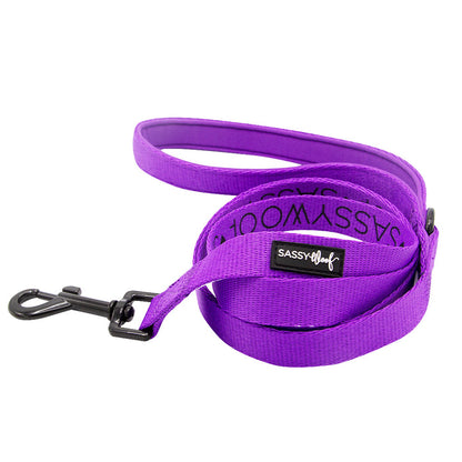 The Sassy Woof Dog Two Piece Bundle in Neon Purple features a coiled leash with a black metal clasp and branded label, ideal for matching with a neon dog harness, shown against a white background.