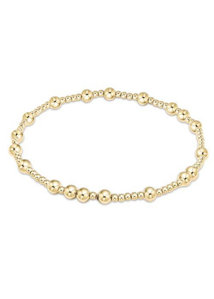 Gold beaded bracelet with alternating bead sizes on a white background
