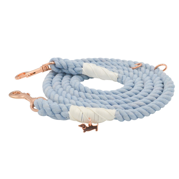 The Hands-Free Rope Leash - Azul by Sassy Woof is a hand-crafted, coiled light blue dog leash featuring elegant rose gold metal clasps, white wrapped accents, and a small dog-shaped charm attached near one clasp.