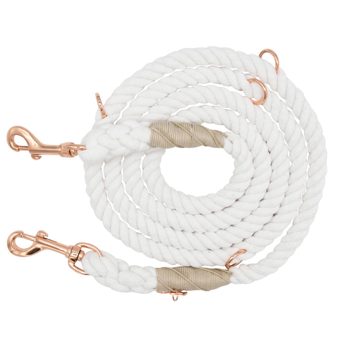 The Sassy Woof Hands-Free Rope Leash - Dove is a coiled white rope dog leash featuring copper-colored metal clips on both ends and beige wrapping near the tips, hand-crafted for quality and durability, displayed on a white background.