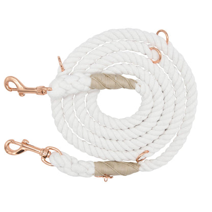 The Sassy Woof Hands-Free Rope Leash - Dove is a coiled white rope dog leash featuring copper-colored metal clips on both ends and beige wrapping near the tips, hand-crafted for quality and durability, displayed on a white background.