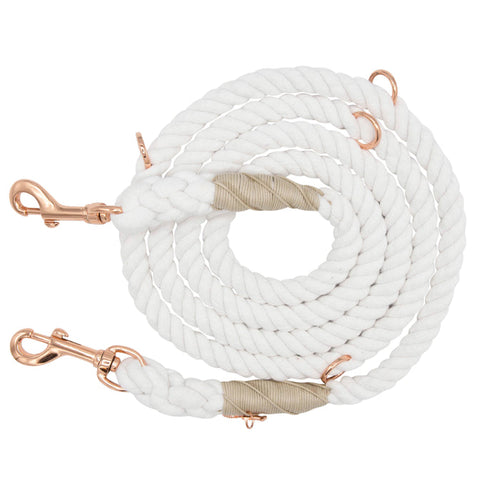 The Sassy Woof Hands-Free Rope Leash - Dove is a coiled white rope dog leash featuring copper-colored metal clips on both ends and beige wrapping near the tips, hand-crafted for quality and durability, displayed on a white background.