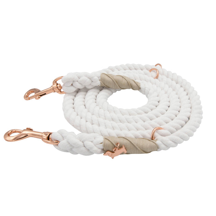 A Sassy Woof Hands-Free Rope Leash in Dove, coiled neatly with rose gold metal clips and beige accents at the ends, displayed on a white background.