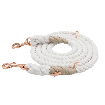 A Sassy Woof Hands-Free Rope Leash in Dove, coiled neatly with rose gold metal clips and beige accents at the ends, displayed on a white background.