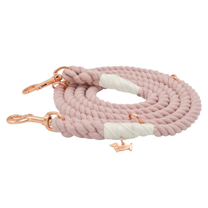 Introducing the Hands-Free Rope Leash - Rose All Day by Sassy Woof, a coiled, pale pink dog leash featuring gold clips, white accents, and a charming gold dog-shaped charm. Hand-crafted for both durability and style, this leash is perfect for your daily walks.