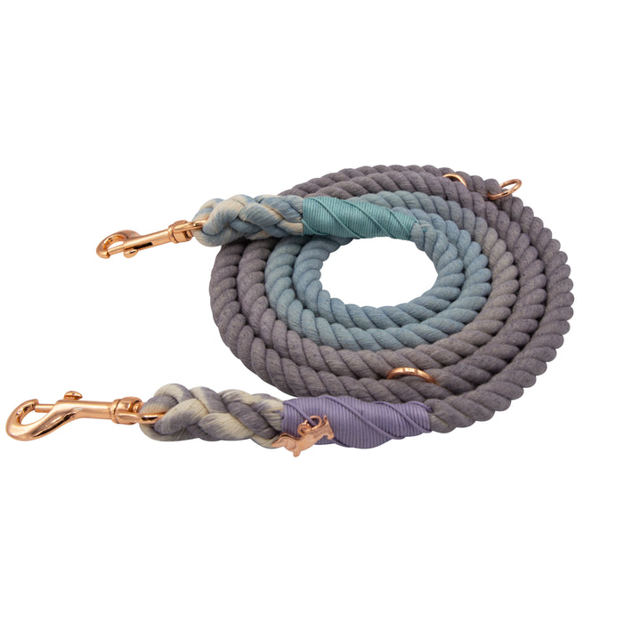 The Sassy Woof Hands-Free Rope Leash - Skyfall is a coiled, multicolored dog leash featuring shades of blue, gray, and beige with rose gold metal clips at both ends secured by decorative knots. This adjustable leash is designed for hands-free convenience.