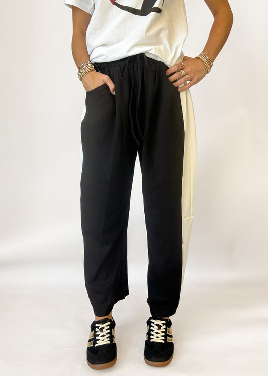 Woman wearing black barrel pants with white stripe on the side