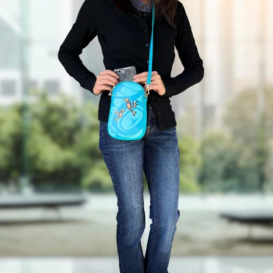 Person holding a blue crossbody bag with a blurred indoor background