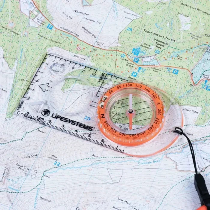 A Lifesystems Hiking Compass placed on top of a topographic map.