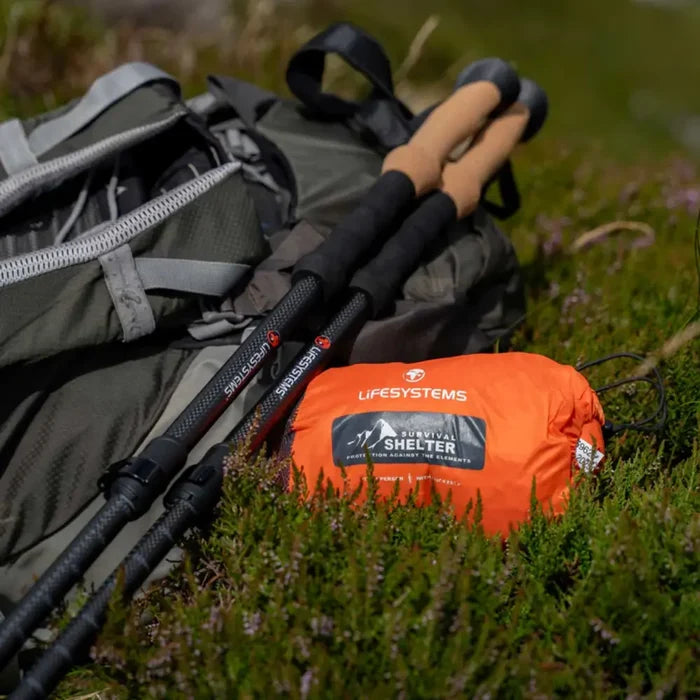 Lifesystems Survival Shelter 1 Man stuff sack with hiking poles on a grassy background