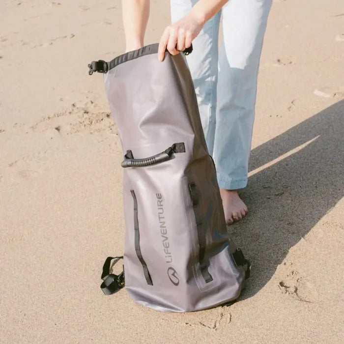 Person removing kit from a Lifeventure Heavy Duty Dry Bag Backpack on a beach