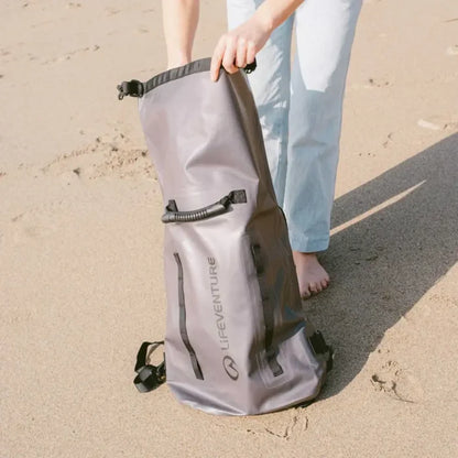 Person removing kit from a Lifeventure Heavy Duty Dry Bag Backpack on a beach