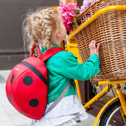Girl wearing a Littlelife Ladybird Kids Backpack whilst looking at a bicycle basket