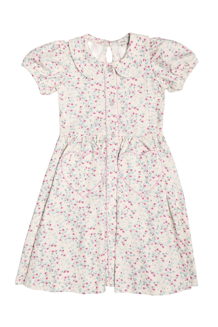 The Mini Alayna Play Dress in Ivory Pansy Trellis by Ivy City Co is a soft cotton-spandex knit girls’ spring dress with short sleeves, pink and blue floral print, Peter Pan collar, button front, and two heart-shaped skirt pockets.