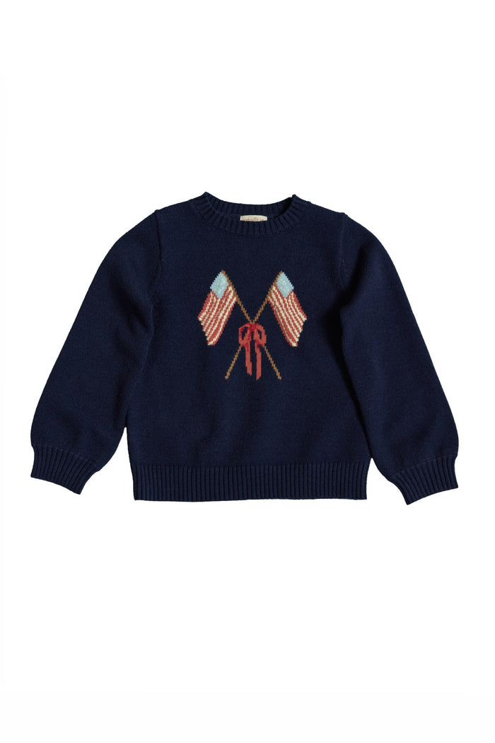 The Ivy City Co Mini Freedom Sweater in Midnight is a navy knit girls' sweater with two crossed American flags and a red bow, perfect for Fourth of July celebrations. Displayed on a white background.