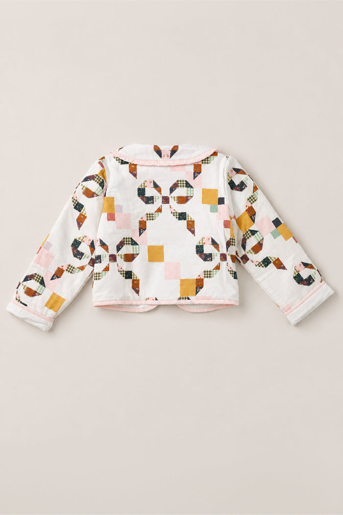 Back view of the Mini Harper Jacket in Quilted Bow by Ivy City Co, a girls’ cotton jacket featuring a colorful patchwork quilt print with pink, mustard, navy, and green geometric patterns, finished with pink trim along the collar and hem.