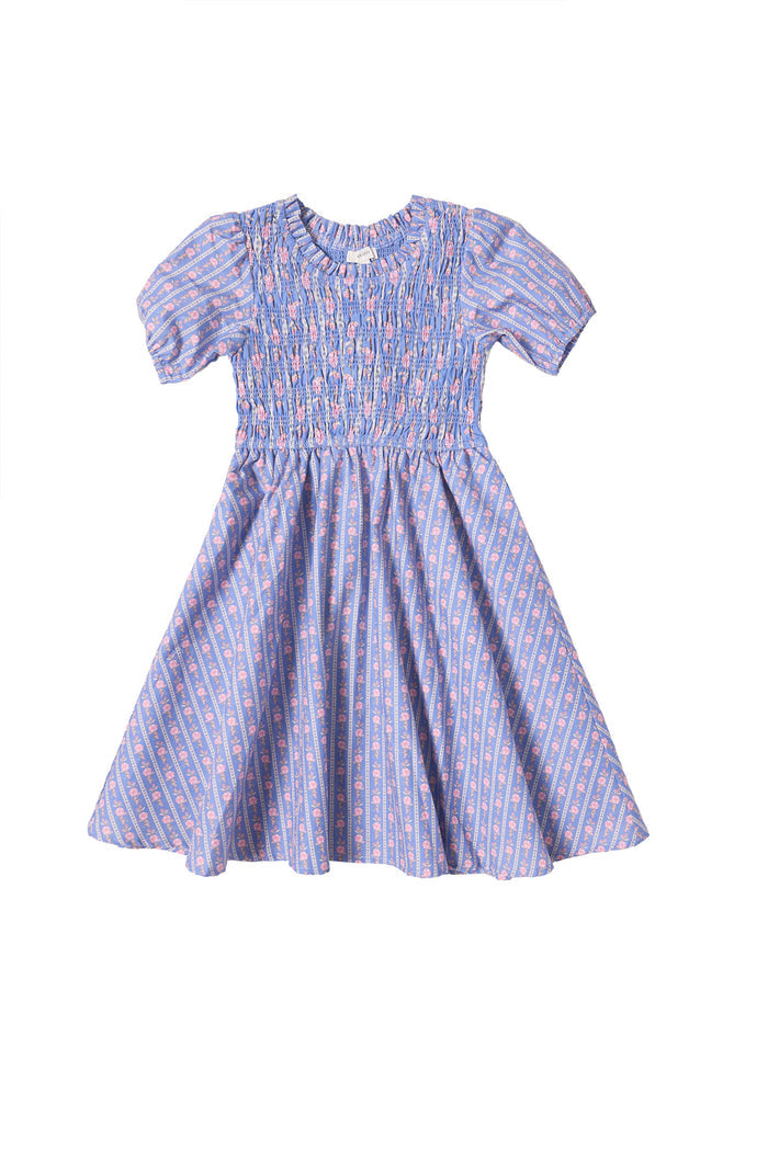 The Mini Mariah Dress in Linear Print by Ivy City Co is a purple, short-sleeved girls midi dress, featuring a smocked bodice and flared skirt with pink and blue floral cotton patterns. Displayed on a white background.