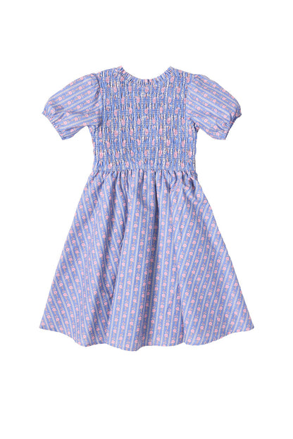 The Mini Mariah Dress in Linear Print by Ivy City Co is a girls’ midi dress in light purple linear floral cotton, featuring a smocked bodice, puffed sleeves, flared skirt, and pink and white florals for a sweet knee-length style.