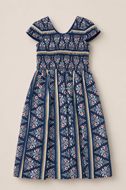 Introducing the Mini Marlow Cap Sleeve Dress in Navy Fleur by Ivy City Co—this charming navy blue cotton midi dress showcases short cap sleeves, a gathered bodice, and a pleated skirt. Adorned with white, red, and yellow floral and geometric striped patterns, it features a V-shaped back neckline for an effortlessly elegant look.