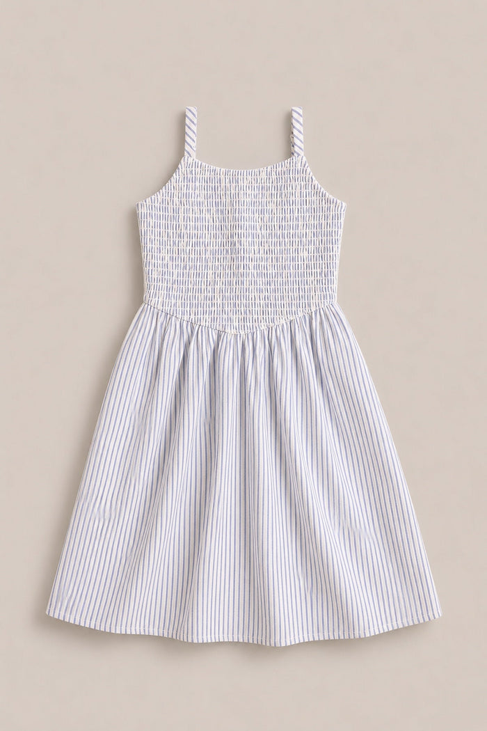 The Mini Maxwell Dress in Blue & White Pinstripe by Ivy City Co is a sleeveless summer dress featuring narrow blue and white vertical stripes, a smocked bodice, and two shoulder straps. Displayed flat on a neutral beige background, this style is perfect for Mom and Me matching looks.
