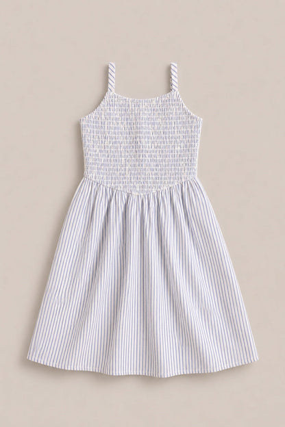 The Mini Maxwell Dress in Blue & White Pinstripe by Ivy City Co is a sleeveless summer dress featuring narrow blue and white vertical stripes, a smocked bodice, and two shoulder straps. Displayed flat on a neutral beige background, this style is perfect for Mom and Me matching looks.