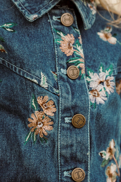 Close-up of the Ivy City Co Mini Posey Denim Jacket in Lovelorn Ditsy Embroidery for girls, featuring delicate floral embroidery and metallic buttons with engraved details; this stylish denim jacket offers charming accents and a modern silhouette.