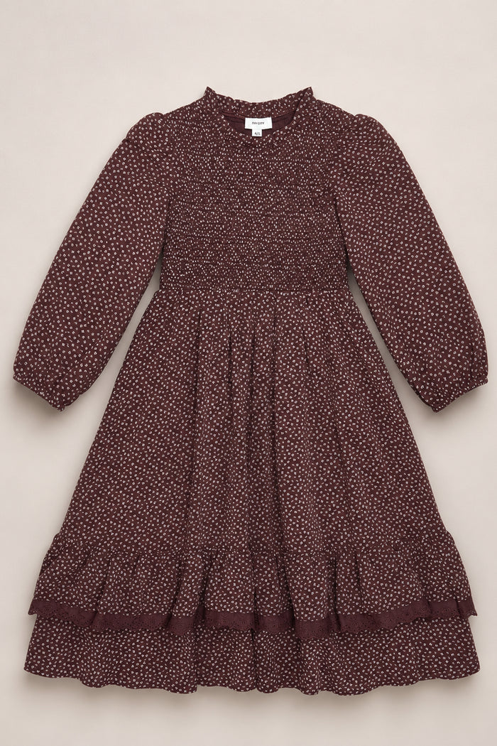 A mahogany ditsy long-sleeve dress, the Mini Presley Maxi Dress by Ivy City Co, is displayed flat on a light background. This charming piece features white polka dots, elegant balloon sleeves, a smocked bodice, ruffled hem, and a gathered skirt—perfectly capturing its playful yet refined spirit.