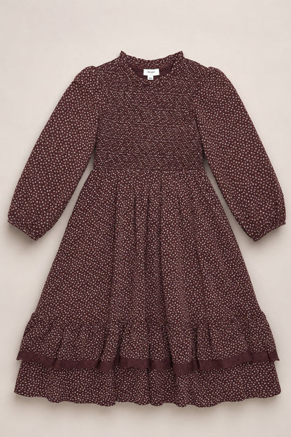 A mahogany ditsy long-sleeve dress, the Mini Presley Maxi Dress by Ivy City Co, is displayed flat on a light background. This charming piece features white polka dots, elegant balloon sleeves, a smocked bodice, ruffled hem, and a gathered skirt—perfectly capturing its playful yet refined spirit.