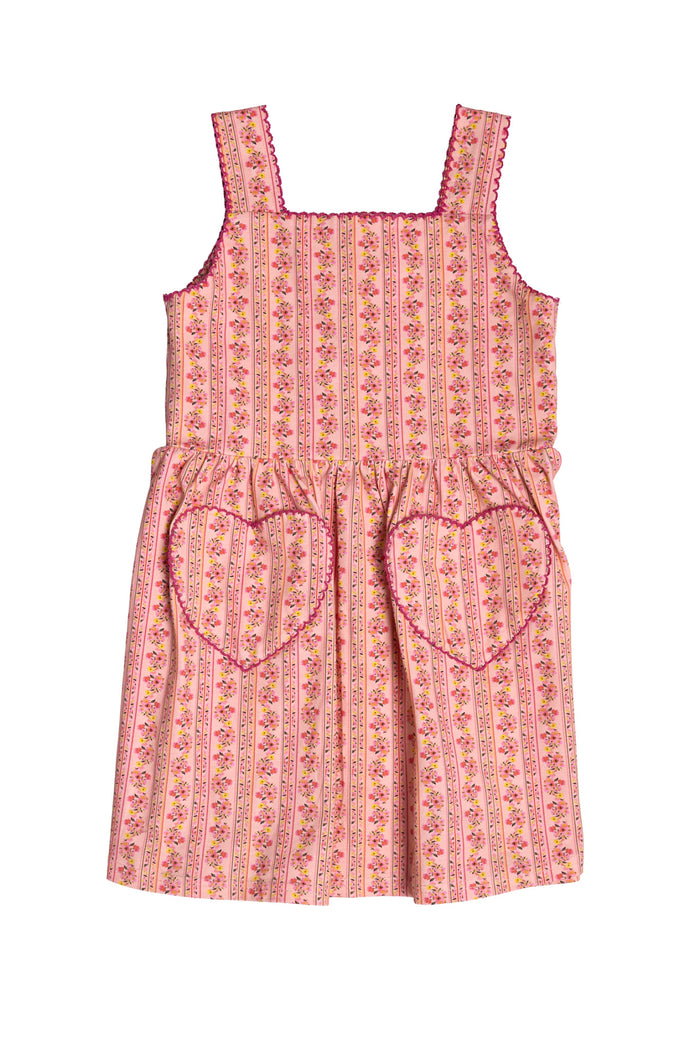 The Mini Rue Play Dress in Handpainted Flora Stripe by Ivy City Co is a charming pink sleeveless dress with vertical floral stripes, a square neckline, heart-shaped pockets, and playful pink trim on the neckline and straps.