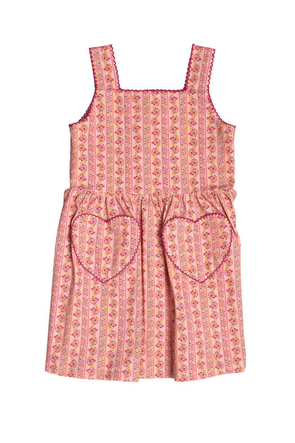 The Mini Rue Play Dress in Handpainted Flora Stripe by Ivy City Co is a charming pink sleeveless dress with vertical floral stripes, a square neckline, heart-shaped pockets, and playful pink trim on the neckline and straps.
