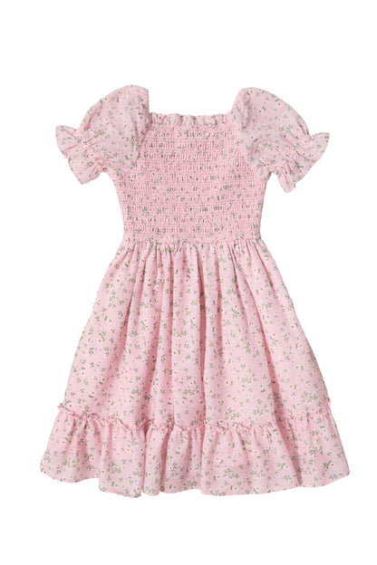 The Mini Valencia Dress in Pink Ditsy Floral by Ivy City Co is a girls' midi dress with short sleeves, a smocked bodice, ruffled hem, and charming green floral print shown laid flat on a white background.