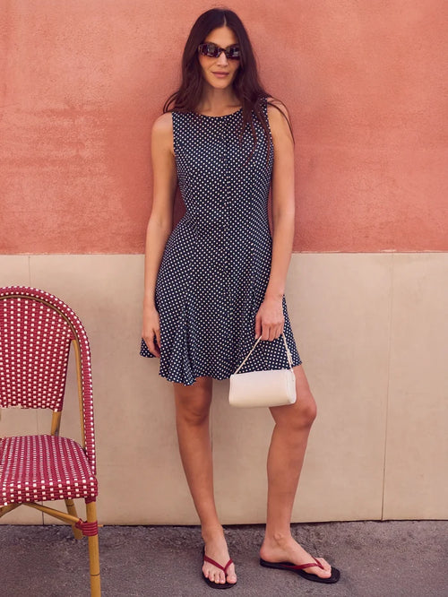 Navy polka dot mini dress with boat neckline, button-front placket and godet hem detailing