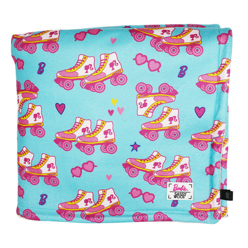 The Pet Blanket - BARBIE™ On a Roll by Sassy Woof features a turquoise sherpa design with pink-and-yellow roller skates, hearts, sunglasses, B logos, and a white patch with the Barbie logo in one corner. Part of the Barbie x Sassy Woof collection.