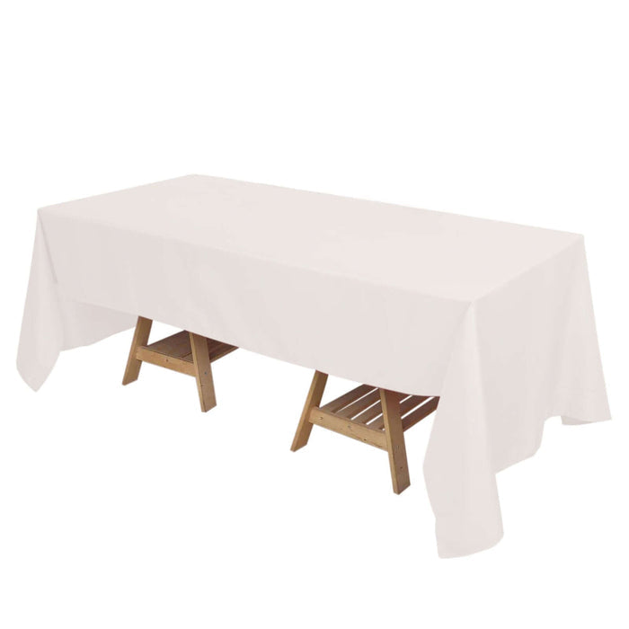 White tablecloth draped over a wooden table on a plain backdrop.